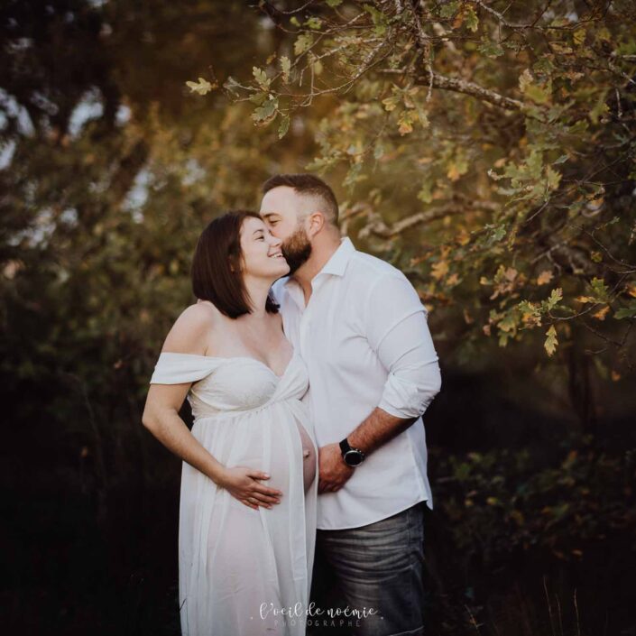 Photo poétique d'une femme enceinte dans une robe blanche de grossesse.